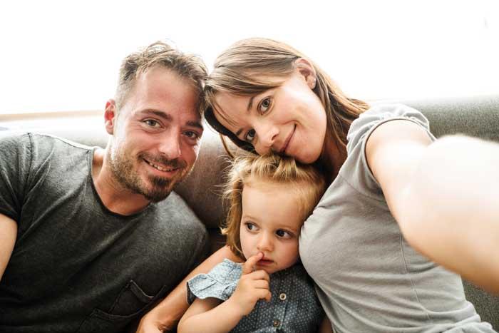 Photo of mum, dad and little girl taking a selfie